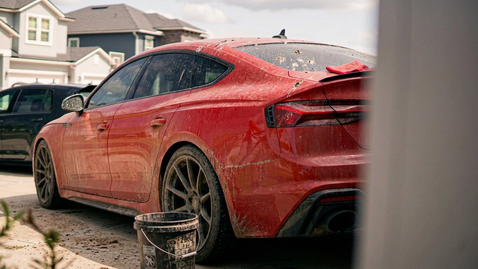 Rinsing a red sedan in a customer's driveway — before